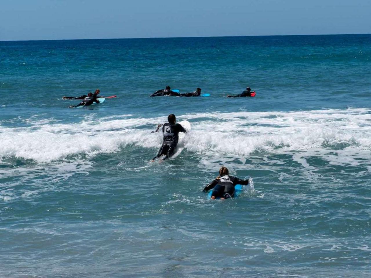 Nico und Alex vom Earlybirdteam paddeln beim TYPO3 Surfcamp aufs Wasser zu einer Gruppe von Surfern