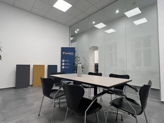 Meetingraum im Earlybird Büro, im Vordergrund ein Tisch, im Hintergrund ein Werbebanner.