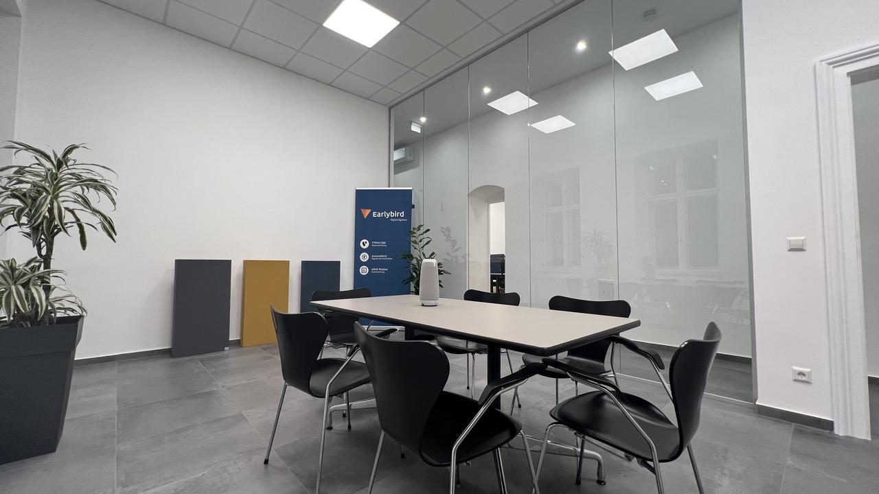 Meetingraum im Earlybird Büro, im Vordergrund ein Tisch, im Hintergrund ein Werbebanner.
