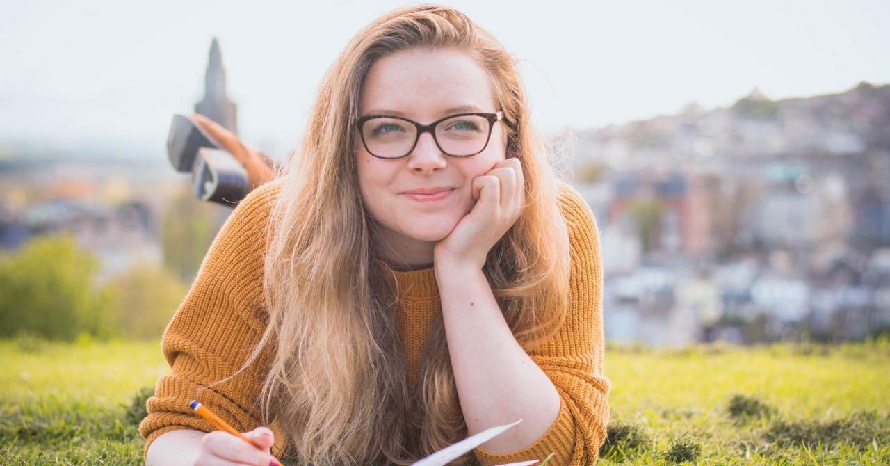 Mädchen liegt in der Wiese und denkt über Texte nach