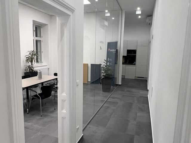 Blick vom Eingang des Earlybird Office in den Gang mit hohen Räumen, grauem Schieferboden und Glaswand.