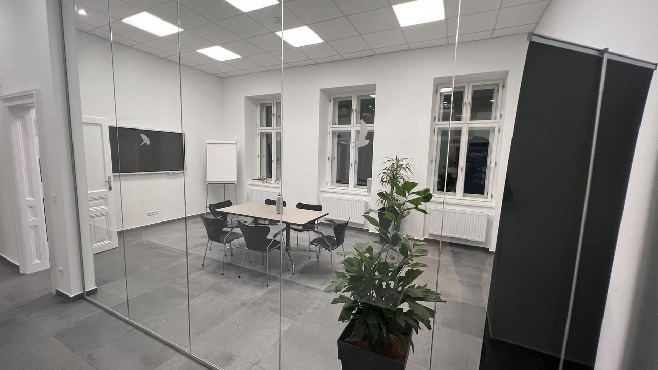 Blick in den Earlybird Meetingraum von außen auf ein analoges und ein digitales Flipchart.